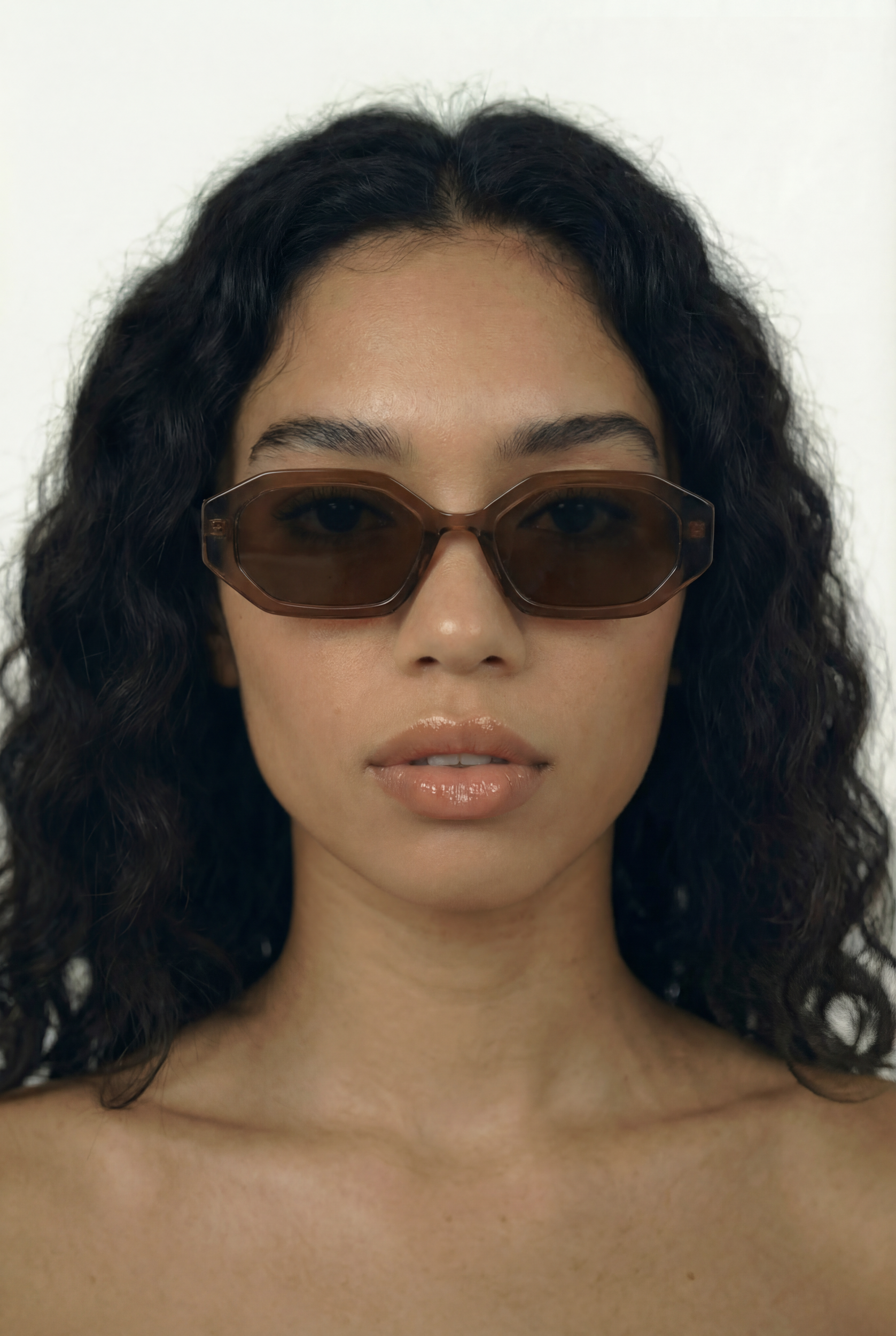 Woman wearing brown RECTANGLE sunglasses with a plain background