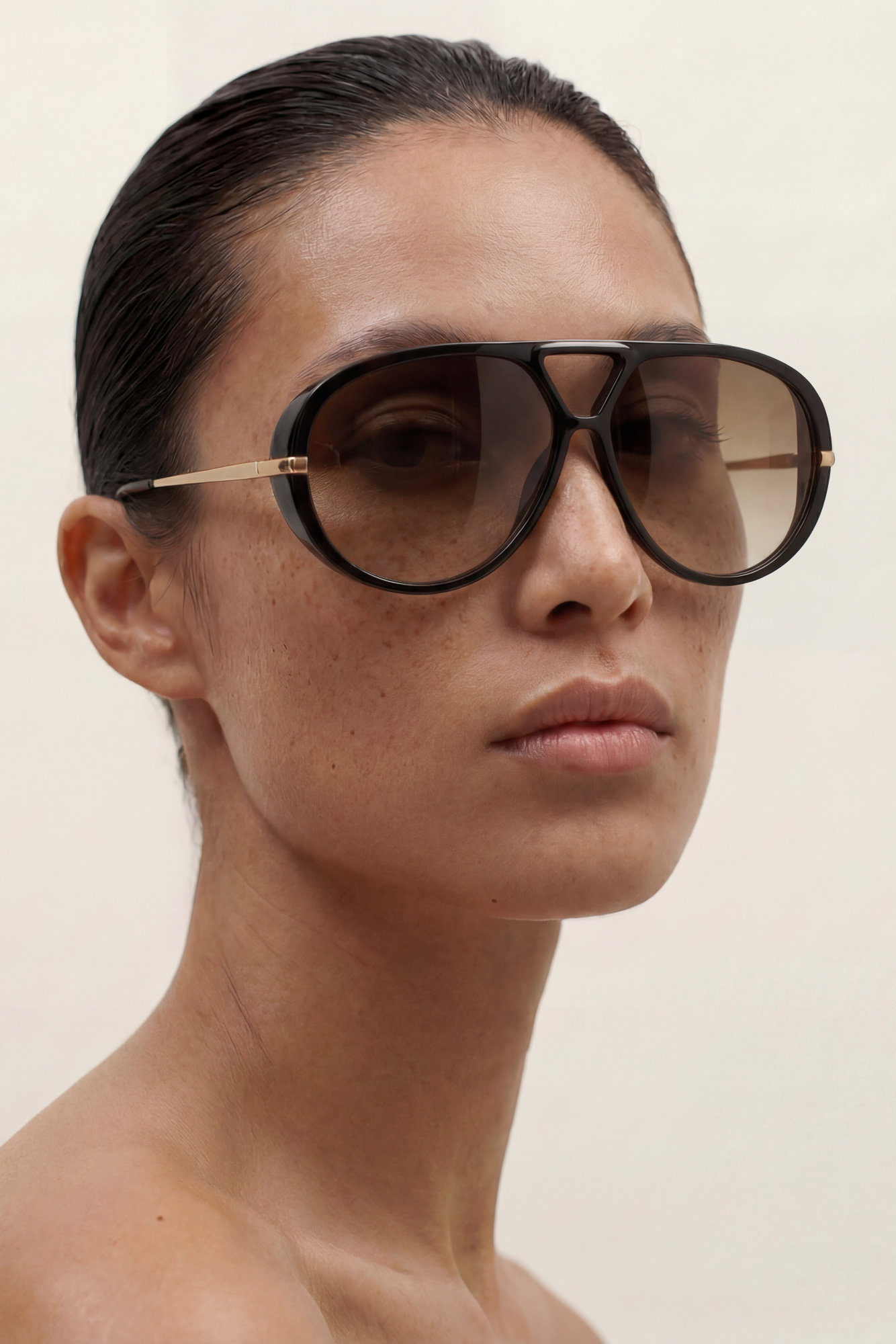 Woman wearing large aviator sunglasses on a plain background