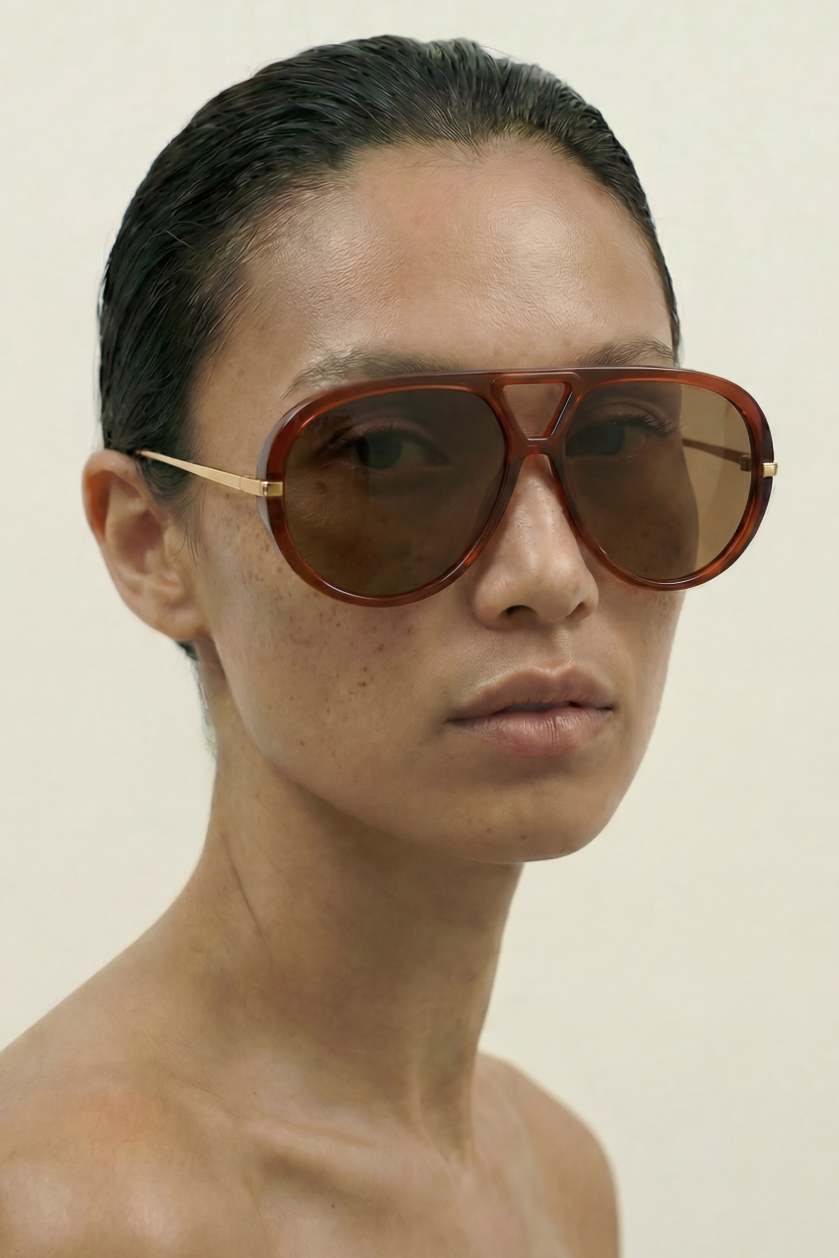 Person wearing large aviator sunglasses against a plain background