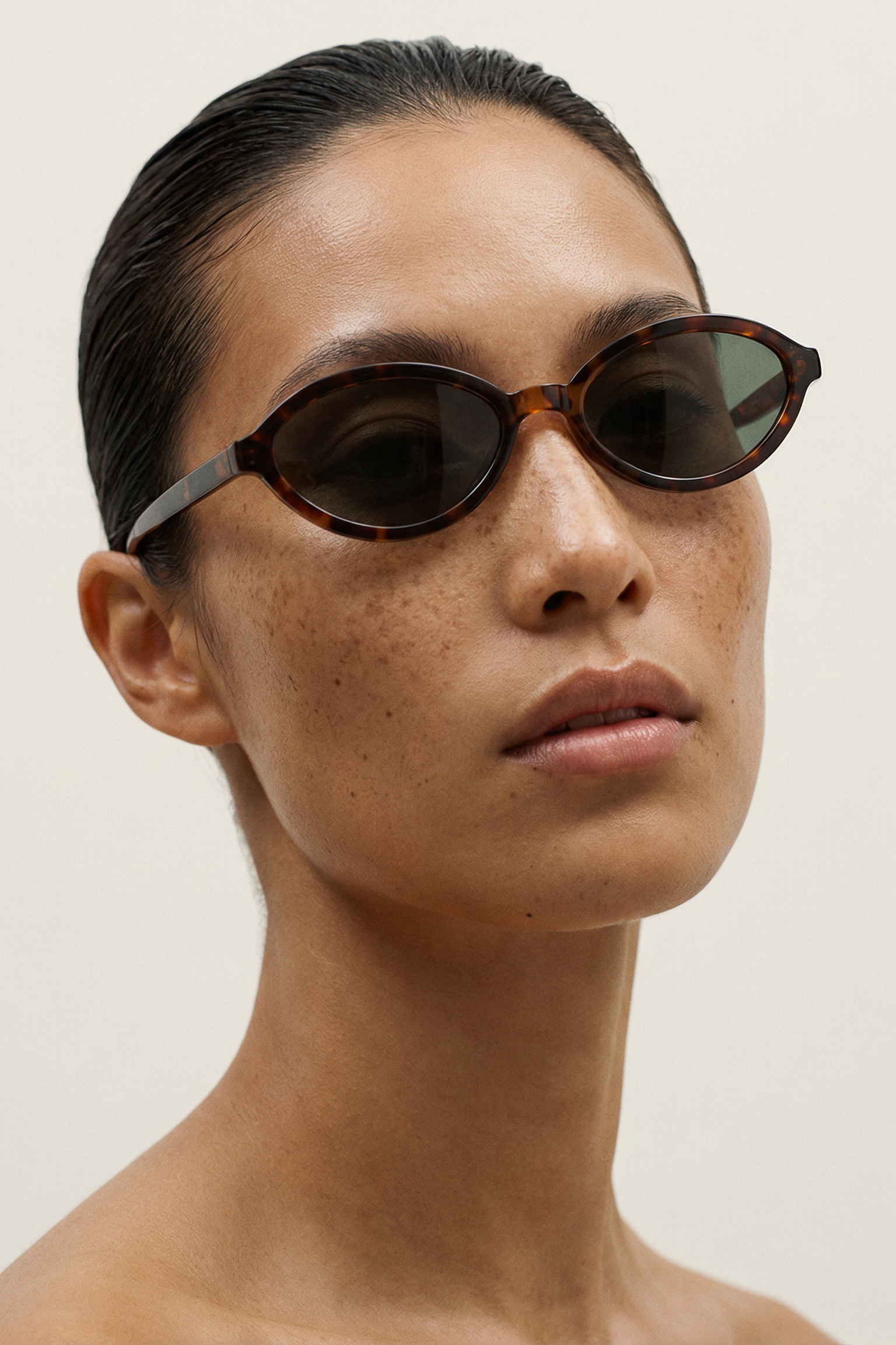 Woman wearing tortoiseshell sunglasses against a plain background