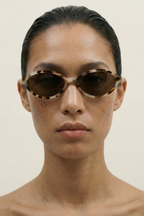 Person wearing tortoiseshell sunglasses against a plain background