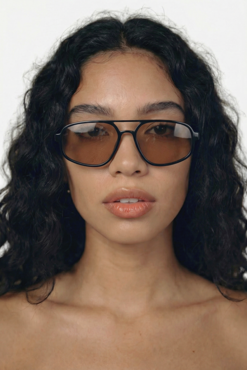 Woman wearing black-framed aviator sunglasses with a plain background