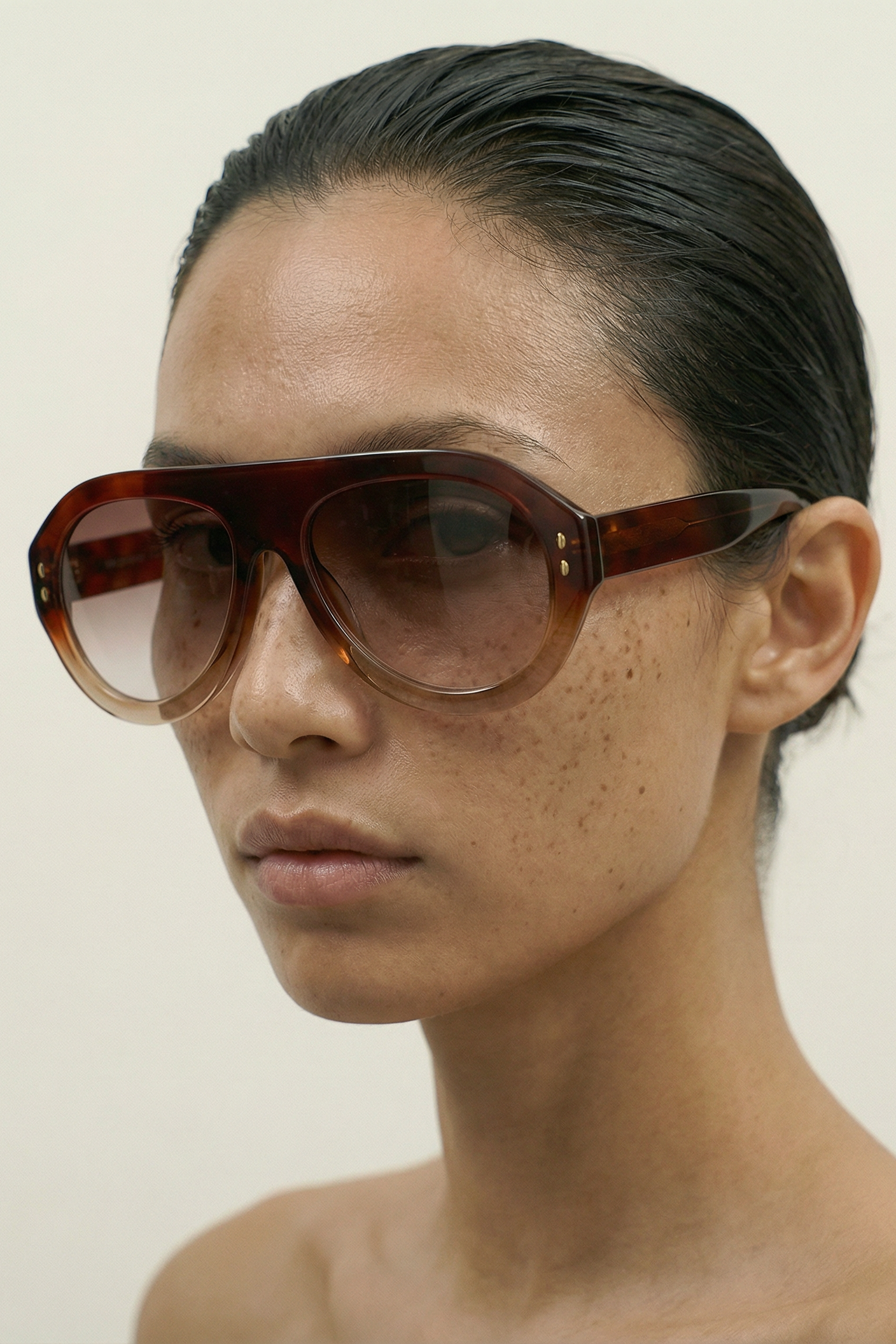 Person wearing a pair of MAROON AVIATOR sunglasses with a neutral background