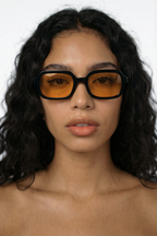 Person wearing black glasses with orange lenses on a white background