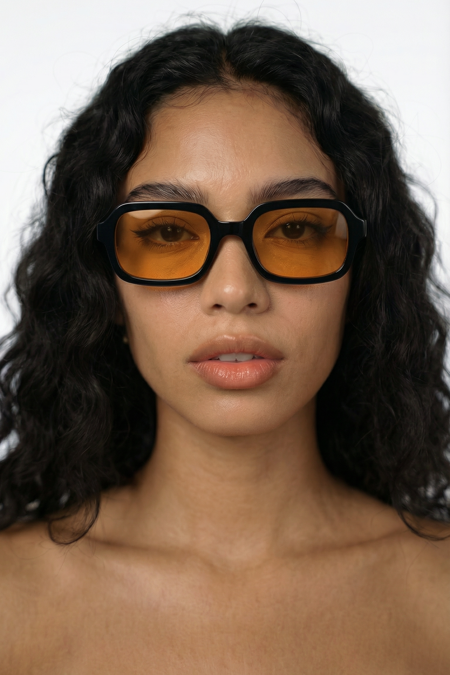Person wearing black glasses with orange lenses on a white background