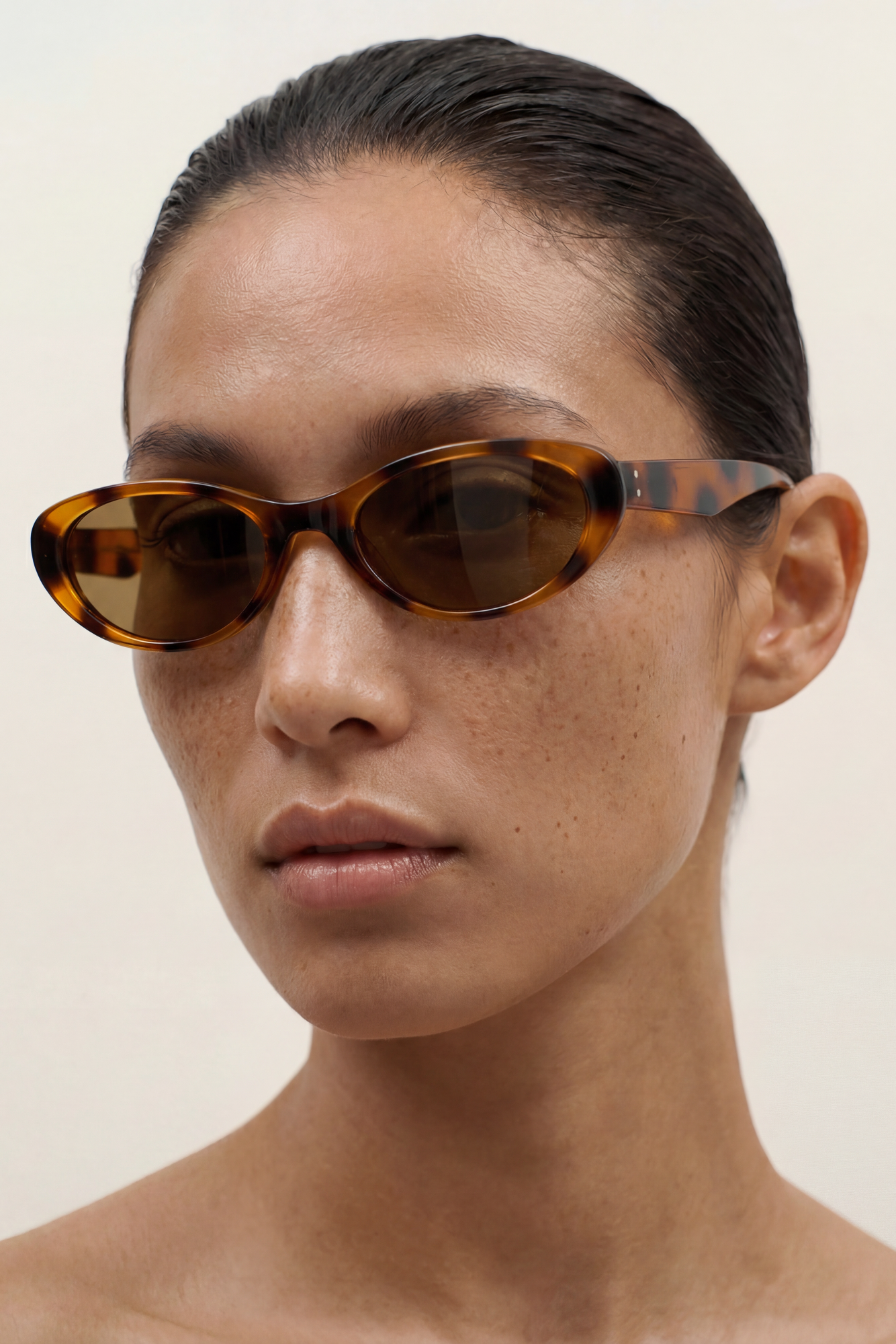 Person wearing a pair of tortoiseshell cat eye sunglasses against a plain background